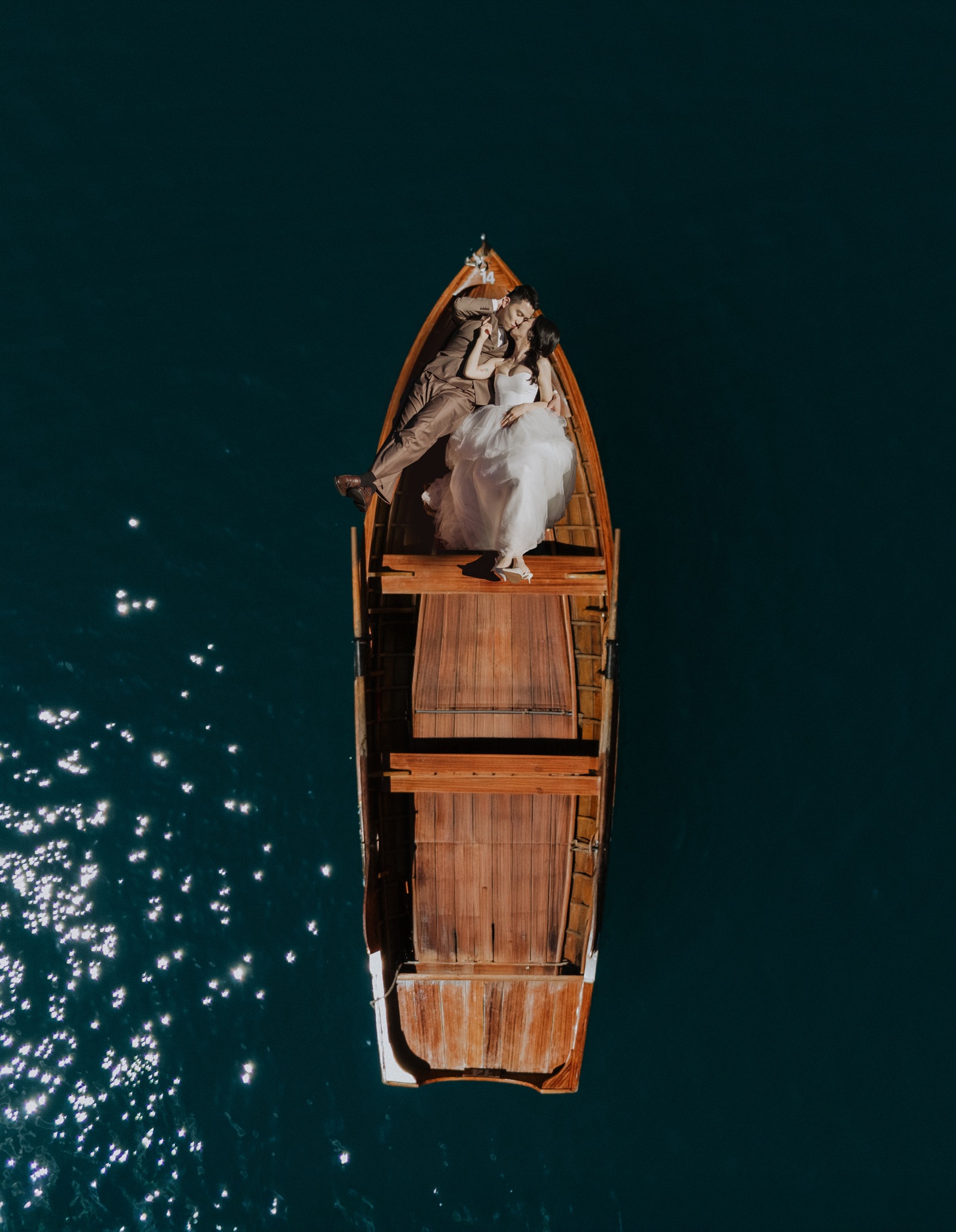 Cathleen and Justin resting together in a wooden boat on deep green water