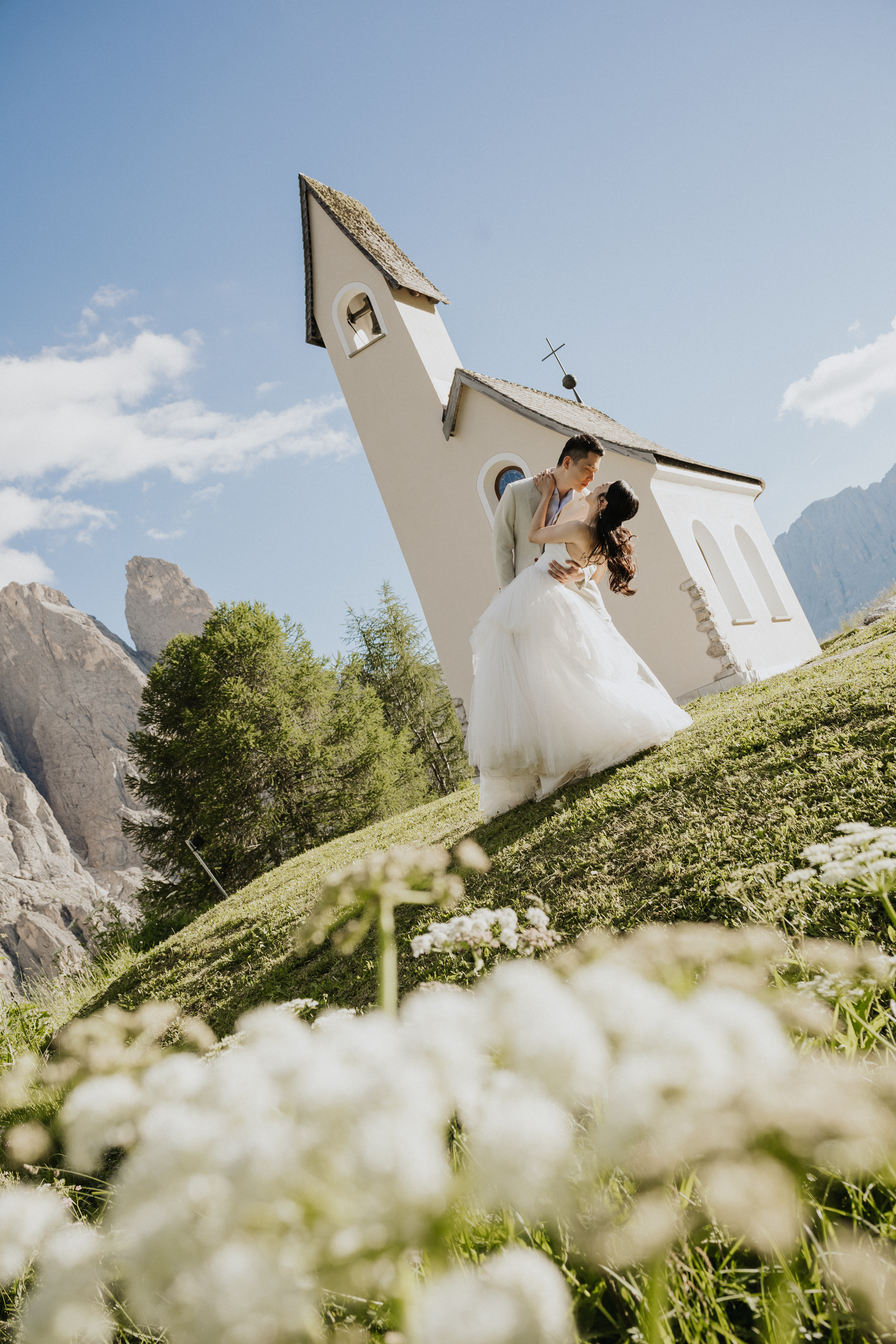 Cathleen and Justin embracing beside a mountain chapel